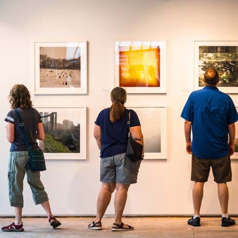 Three people facing a wall with art being displayed